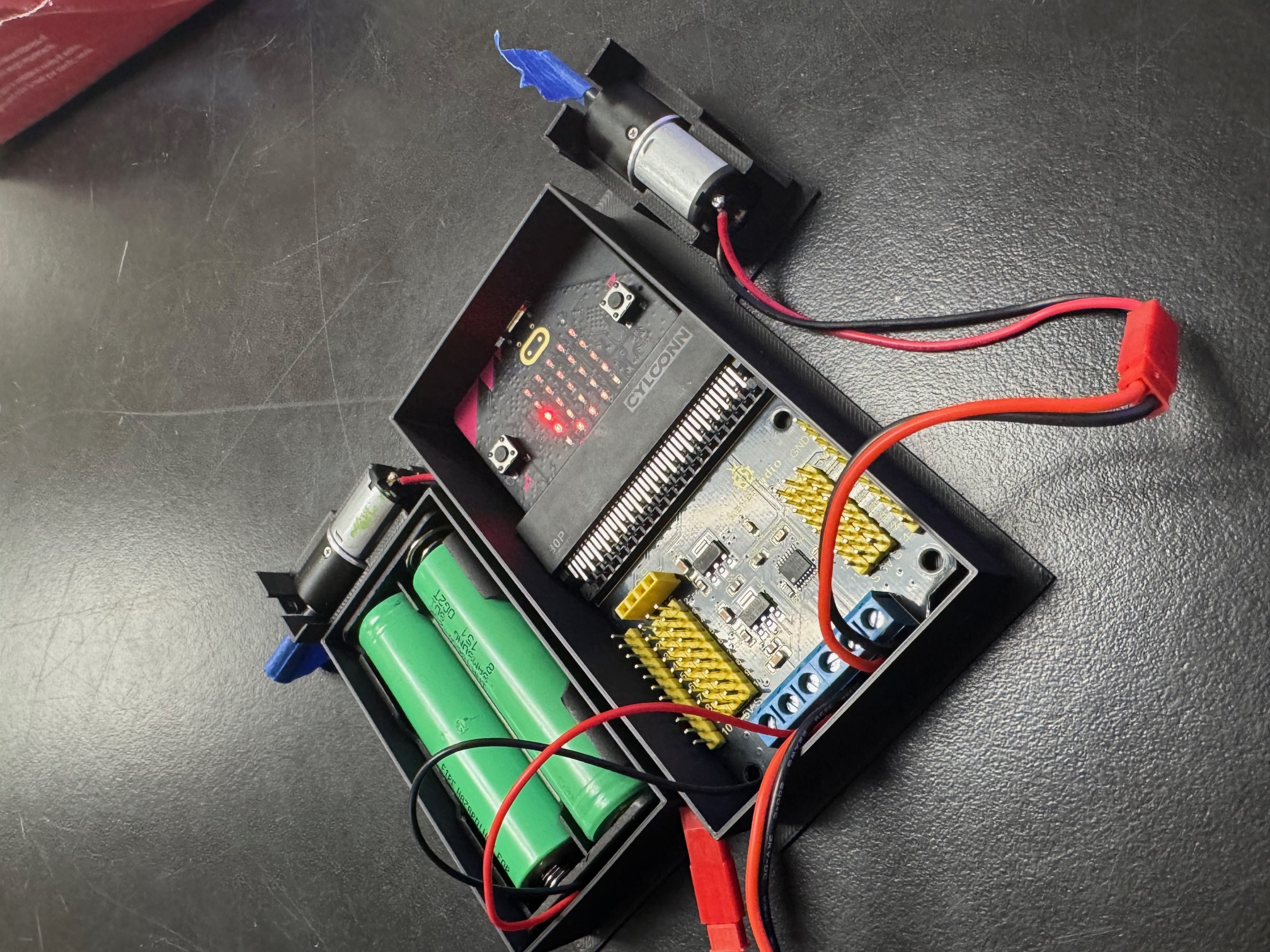 Completed RC car base with the Micro:bit V2, Keyestudio motor driver HAT, and wiring installed.
